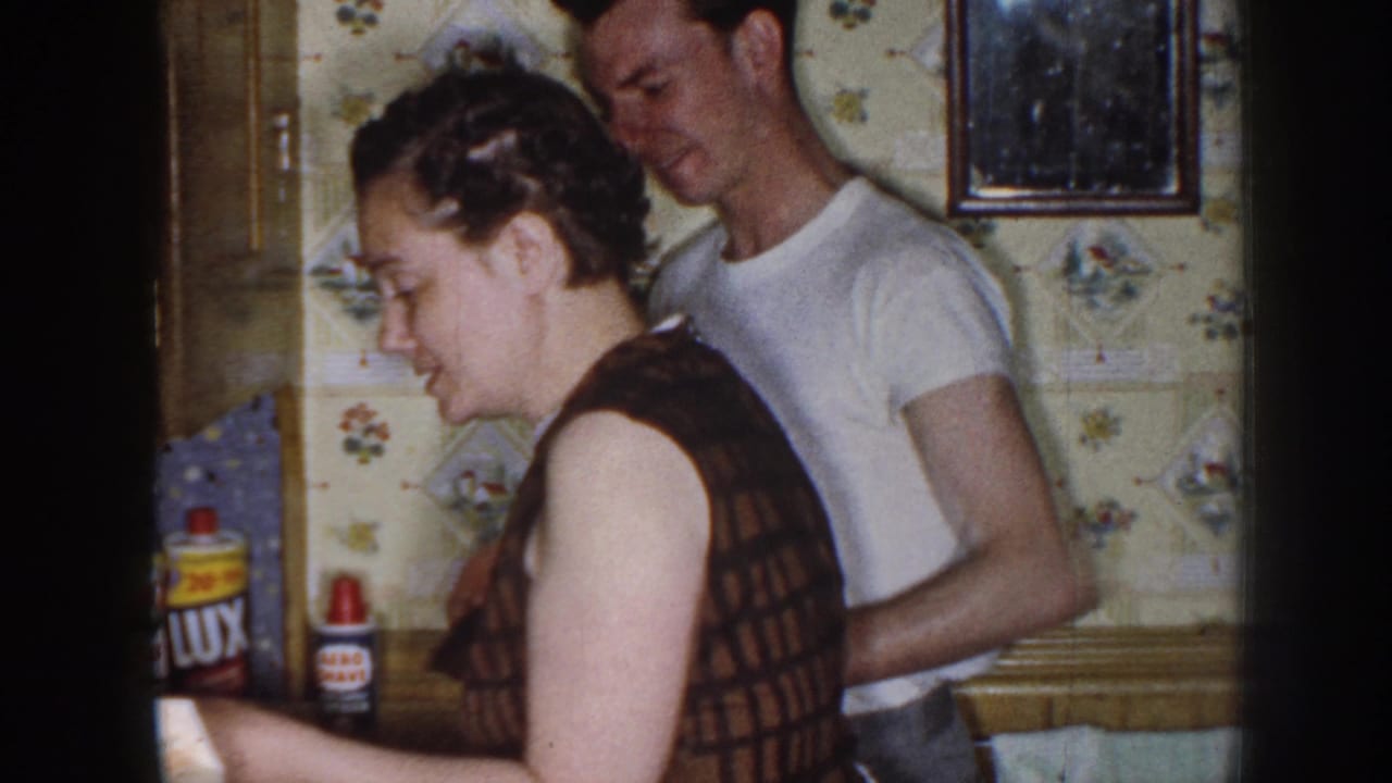 Woman at a kitchen counter with a man standing close behind her.