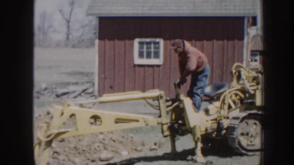 A brief exterior frame shows a man on yellow machinery near a red outbuilding, likely from the same 1958 Nebraska home-movie reel.