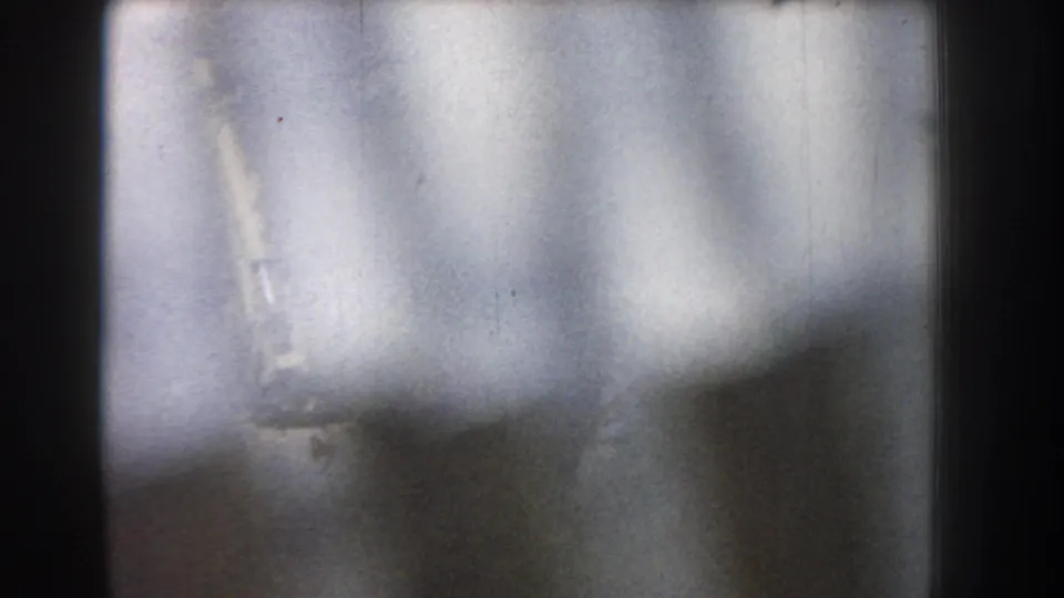 The final 8mm frame is mostly out of focus, showing blurred light areas and dark film-edge shapes with little readable detail.