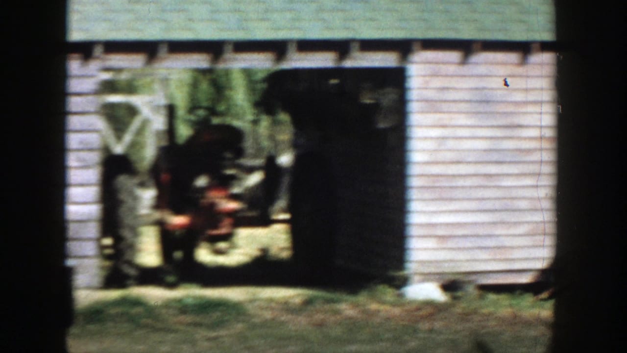 1958 Michigan 8mm frame showing a weathered wooden shed with an open bay and shadowed interior.