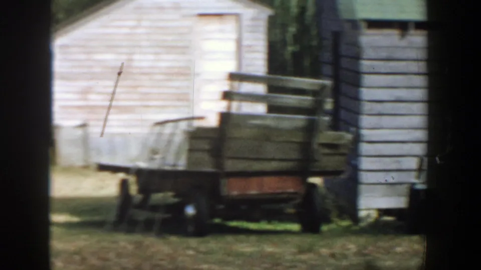 Small utility trailer parked near weathered wooden outbuildings in rural Michigan, 1958.