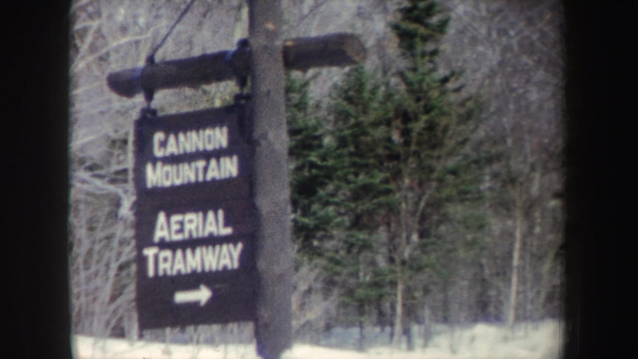 Wooden sign reading Cannon Mountain Aerial Tramway beside snowy trees.