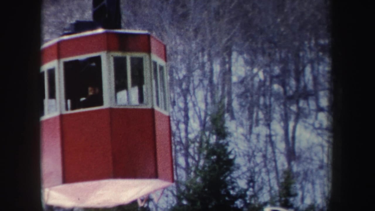 1962 New York 8mm frame showing a red cable-car cabin with passengers visible through windows against a wooded background.