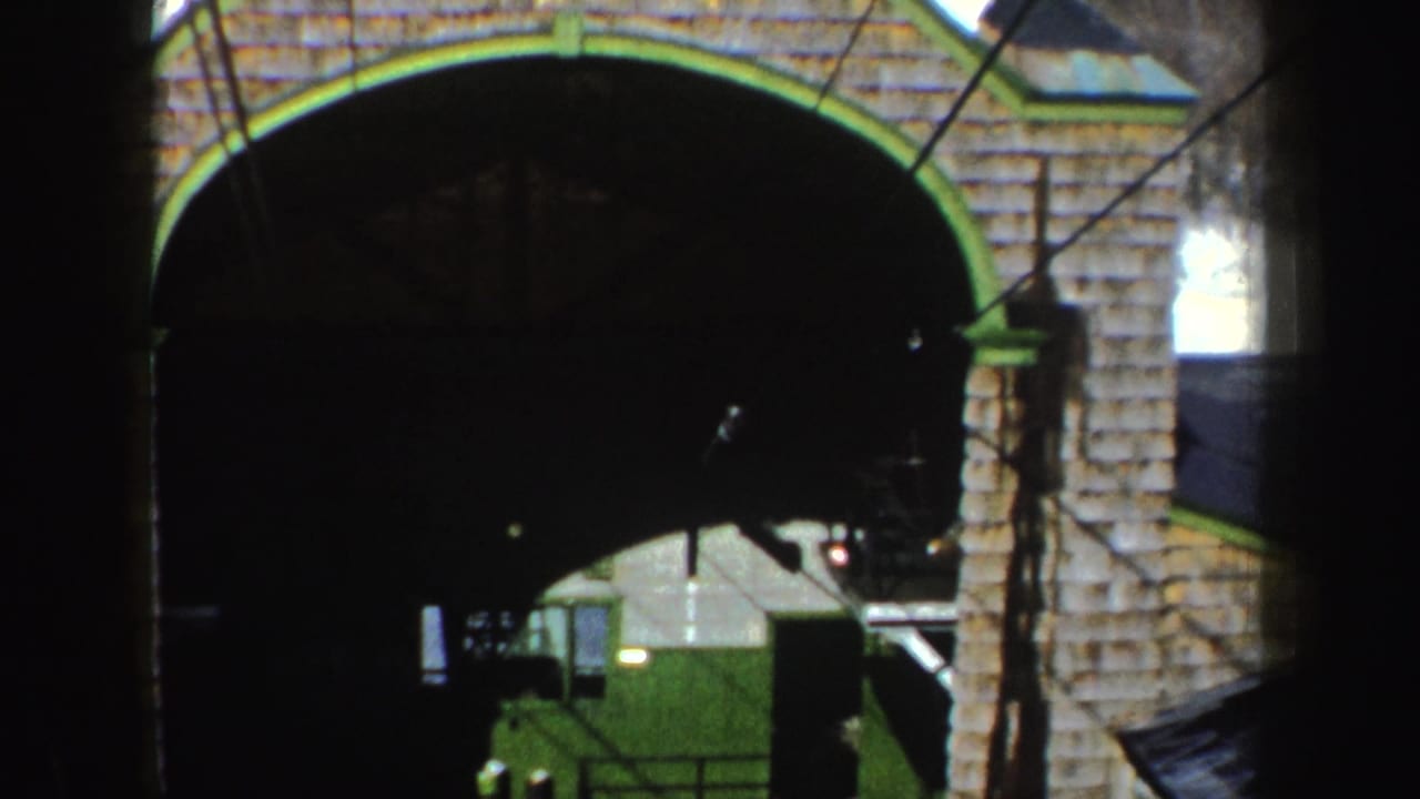 1962 New York 8mm frame showing a brick arched entrance with green trim, partly obscured by dark foreground bars.