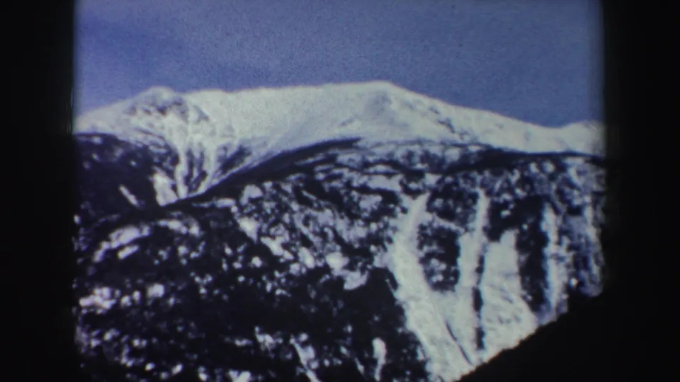 1962 New York 8mm frame of a snowy mountain peak and forested slopes, likely part of the same skyride view.