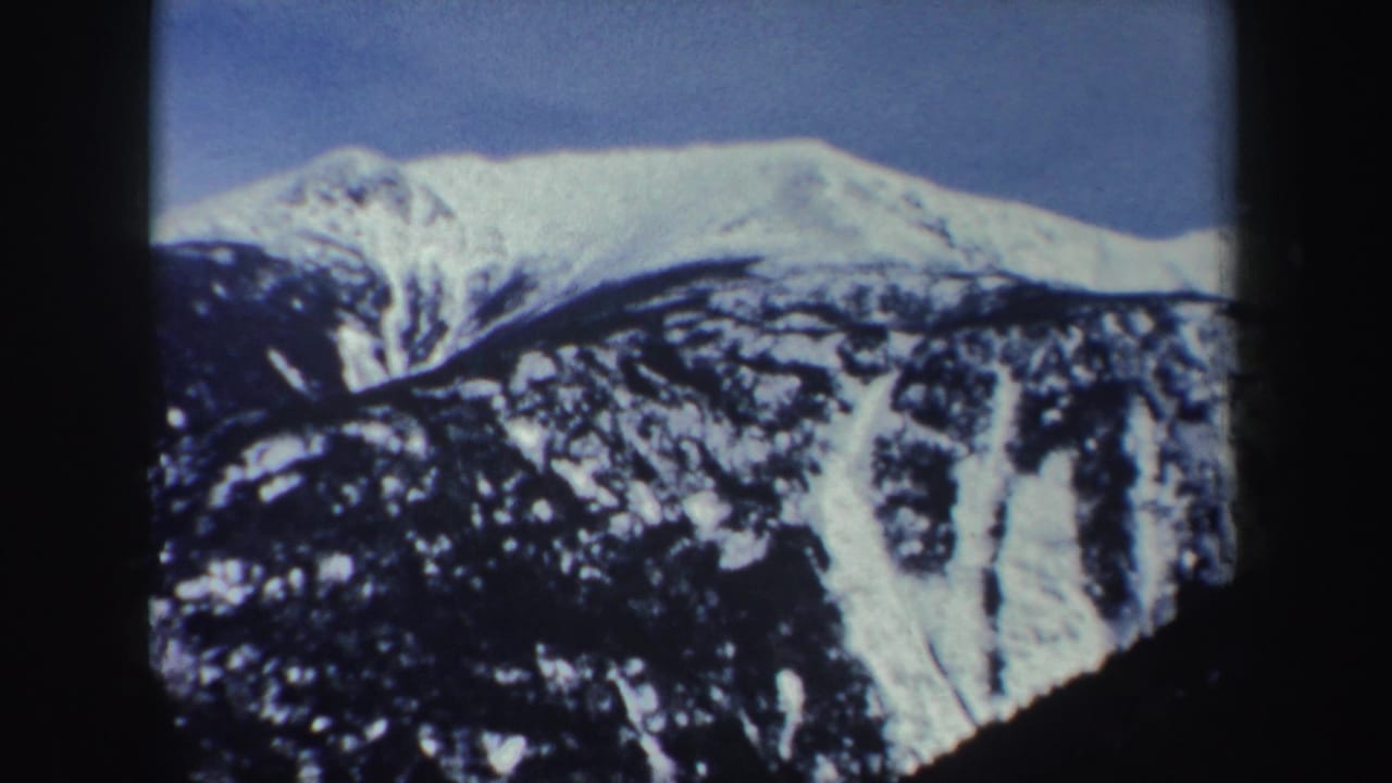 Snowy mountain ridge seen through dark vertical cable-car framing.