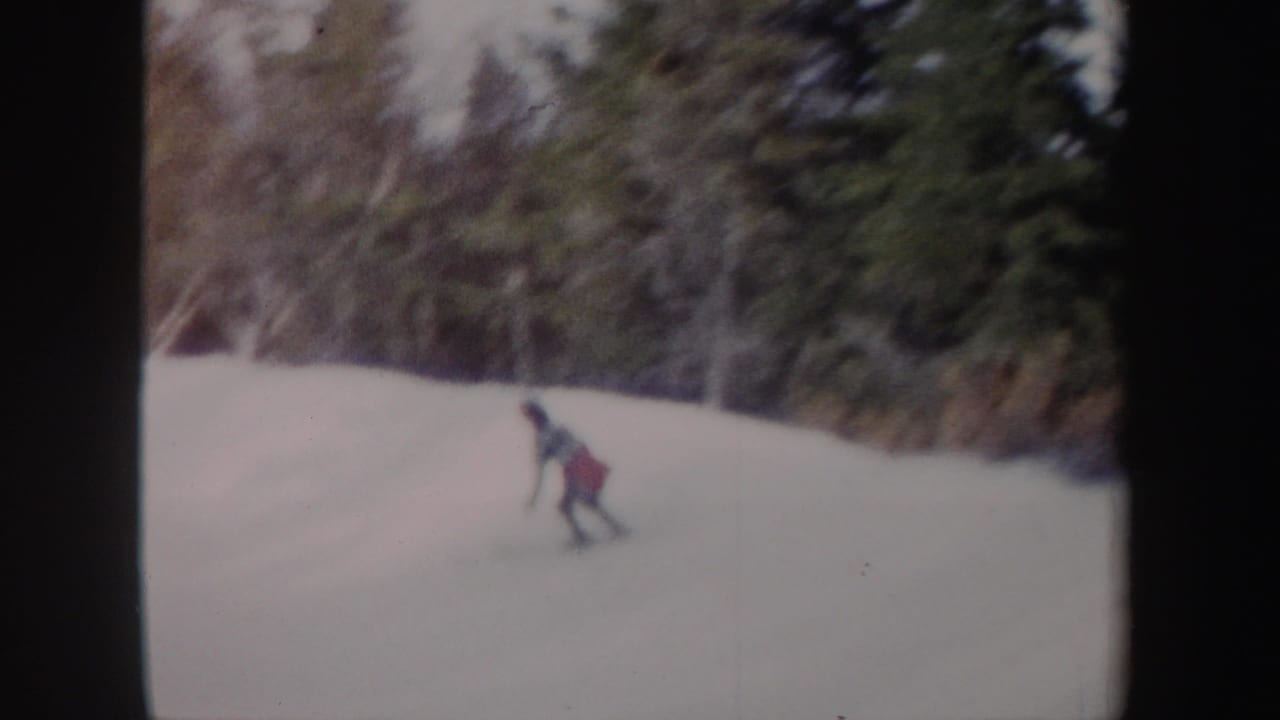 1962 New York 8mm frame of a distant young rider in winter clothing moving down a snowy forest slope.