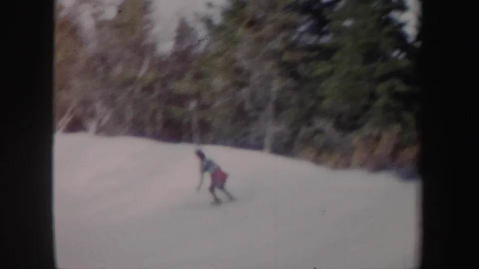 1962 New York 8mm frame of a distant young rider in winter clothing moving down a snowy forest slope.