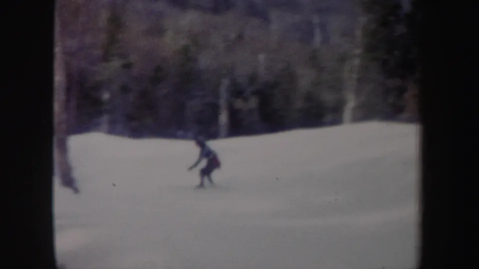 A distant rider moves across the snow in a wooded New York setting, captured on soft 8mm home-movie film.