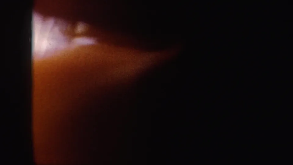 A dark 8mm frame from the end of the snowy downhill clip, showing warm reddish exposure and heavy shadow.