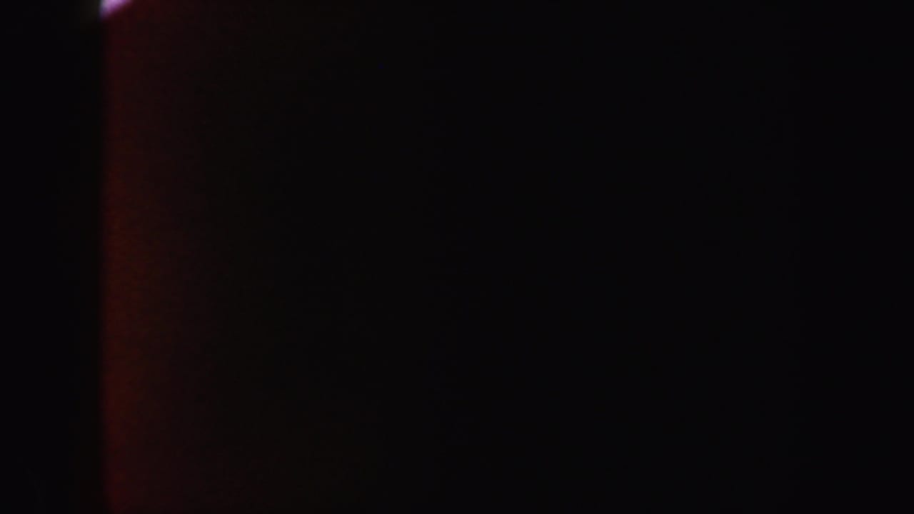 Mostly black frame with faint warm red-orange vertical light along the left edge.
