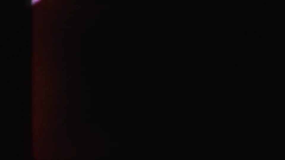 1962 8mm frame from New York showing a dark abstract field with a faint red-orange vertical light leak at the edge.