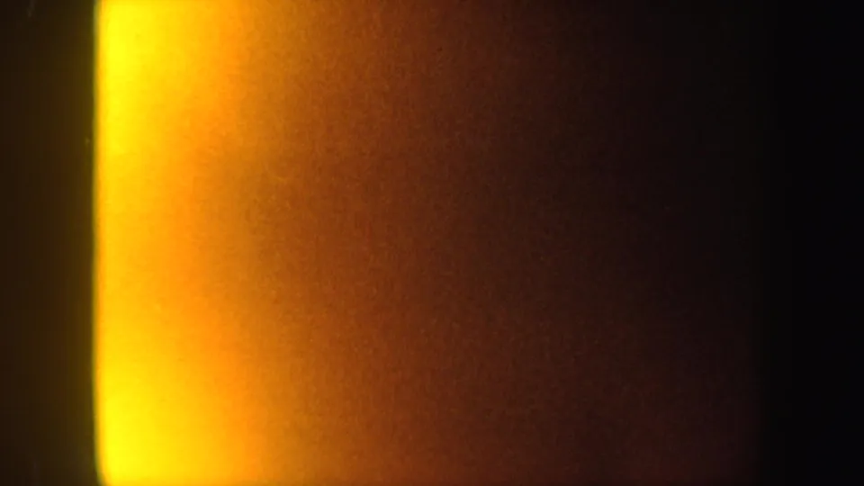 1962 8mm New York frame with a strong yellow-orange vertical glow and dark surrounding exposure.