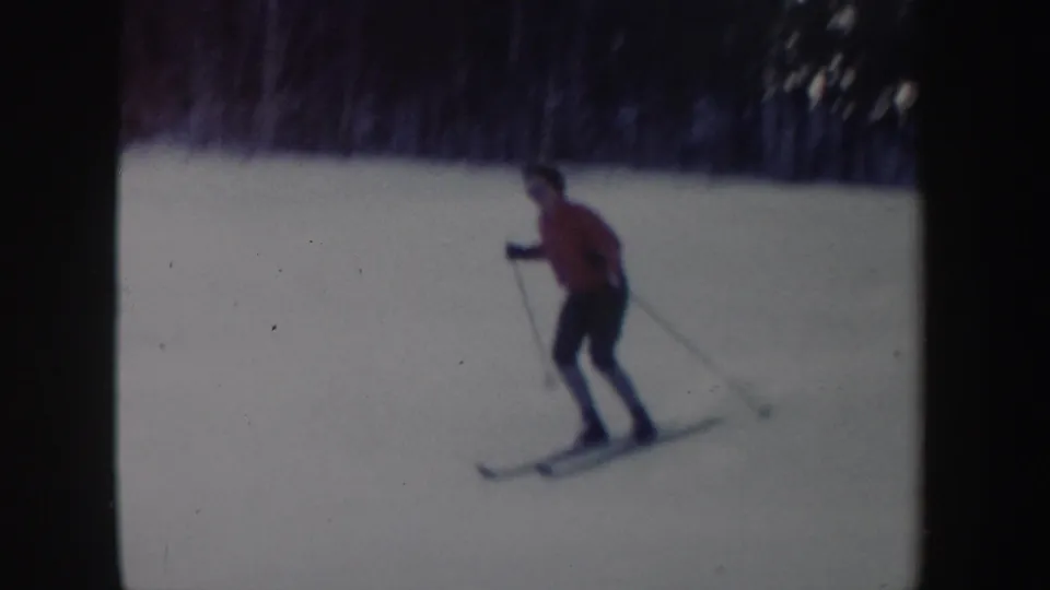 1962 New York 8mm frame of a skier in a red top and dark pants gliding across a snowy hill under soft, faded color.