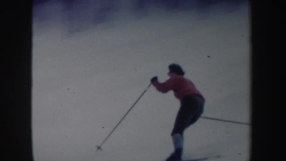 Closer 1962 New York 8mm view of the skier leaning forward with poles while turning on a snowy slope.