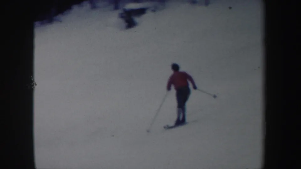 1962 New York 8mm frame showing the skier from behind as they move away across an open snowy slope.