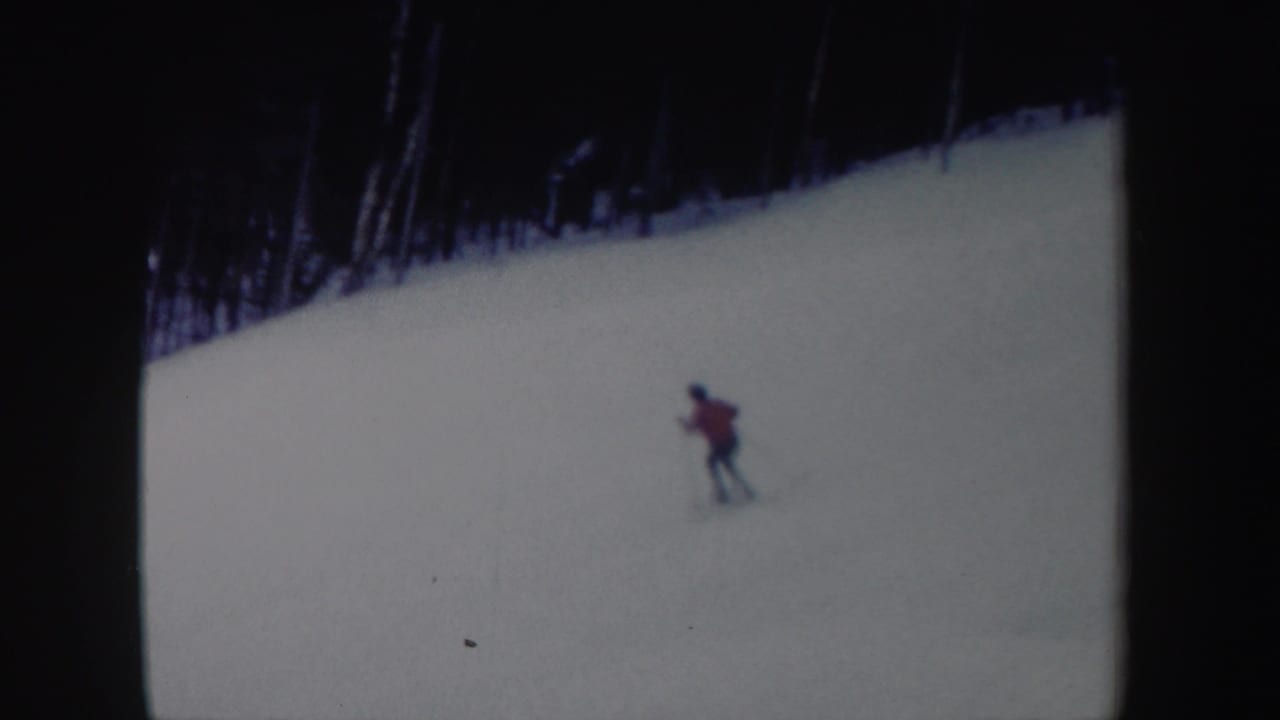 A distant skier in a red jacket traverses a broad snowy New York slope in this 1962 8mm home-movie frame.