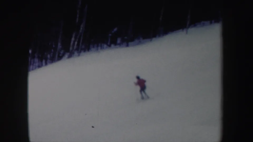 A distant skier in a red jacket traverses a broad snowy New York slope in this 1962 8mm home-movie frame.