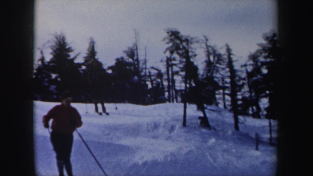 1962 New York 8mm frame showing a skier in a red jacket approaching the camera on a snow-covered wooded slope.