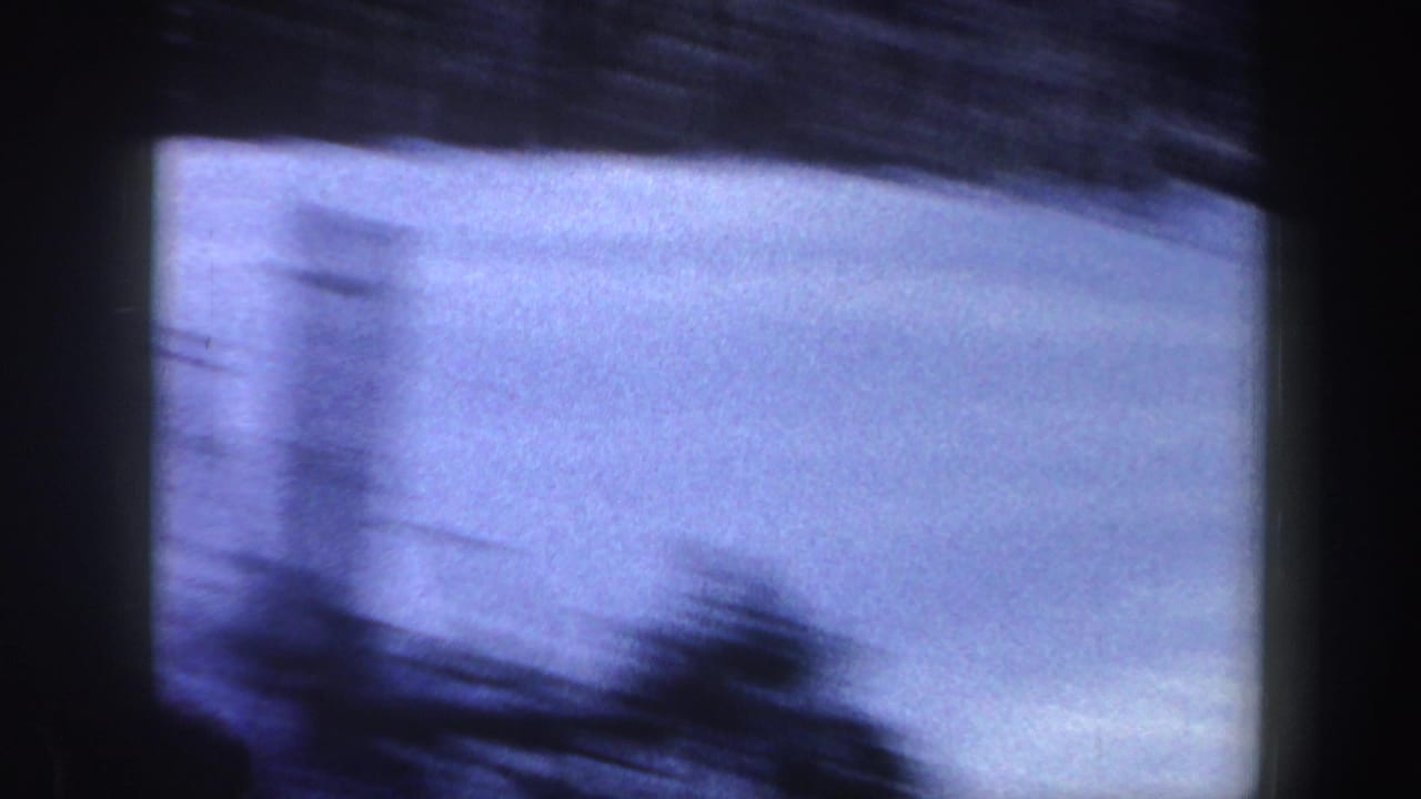 Soft, blue-tinted 8mm view of a snowy slope in New York, 1962, with motion blur and dark frame borders.