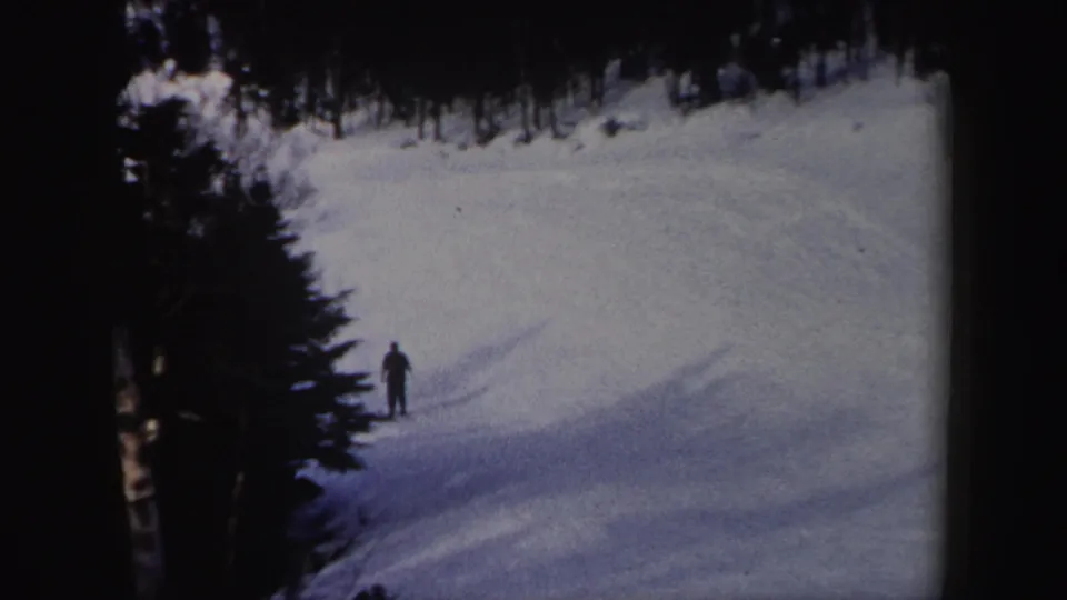 Near the end of the 1962 New York clip, the lone skier is framed from a distance on a broad snowy slope with trees nearby.