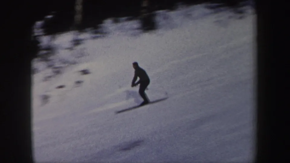 The skier continues across a dim snowy hillside, silhouetted against the 1962 New York winter landscape.