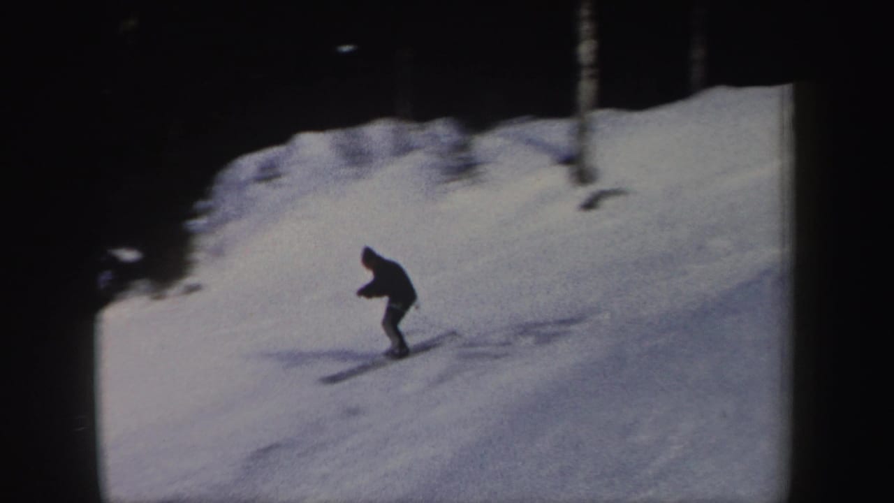 Skier in dark clothing descending a snowy slope near trees.