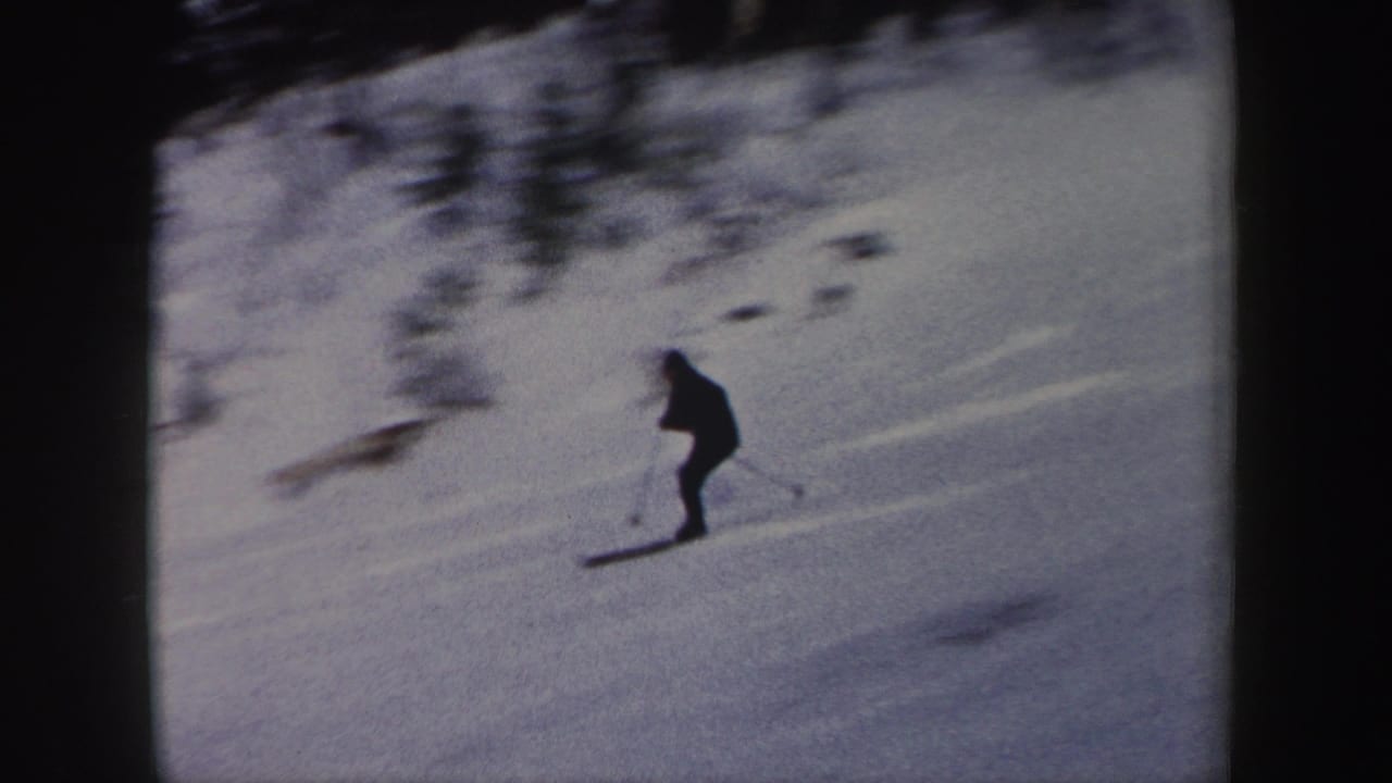 The skier continues across the snow-covered hillside, framed by dark trees in vintage 8mm footage from New York.