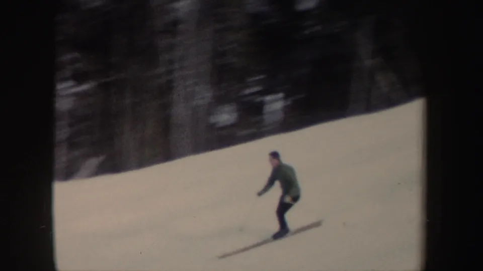 A closer frame shows the lone skier leaning into a downhill run, with wooded terrain behind him.