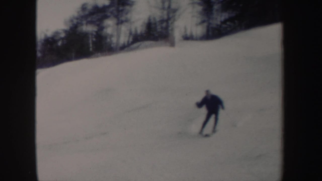 A skier in dark clothing turns across a bright snowy New York slope in soft, grainy 8mm footage from 1962.