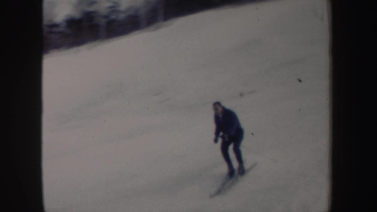 Skier in a dark coat turning on a snowy slope.