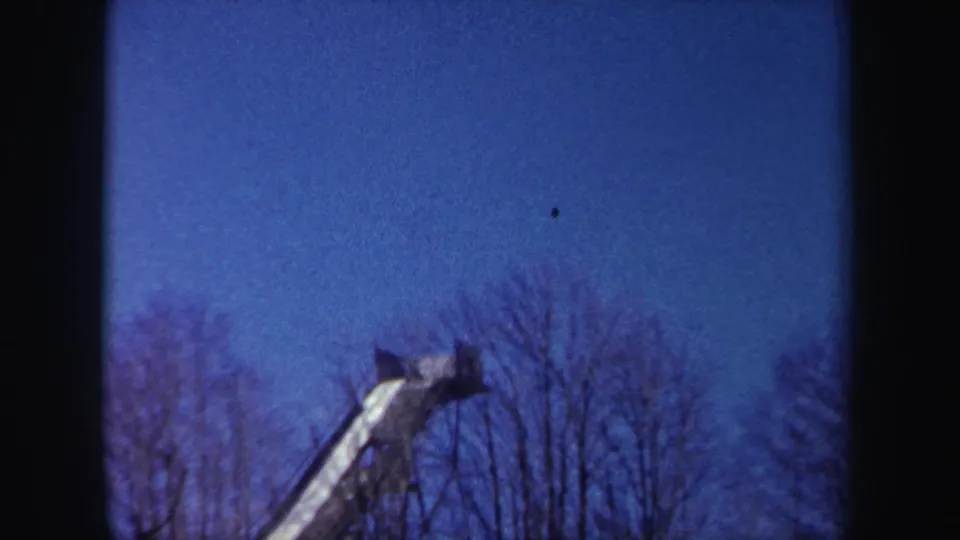 1962 New York 8mm frame looking upward at the top of an elevated structure above winter trees.
