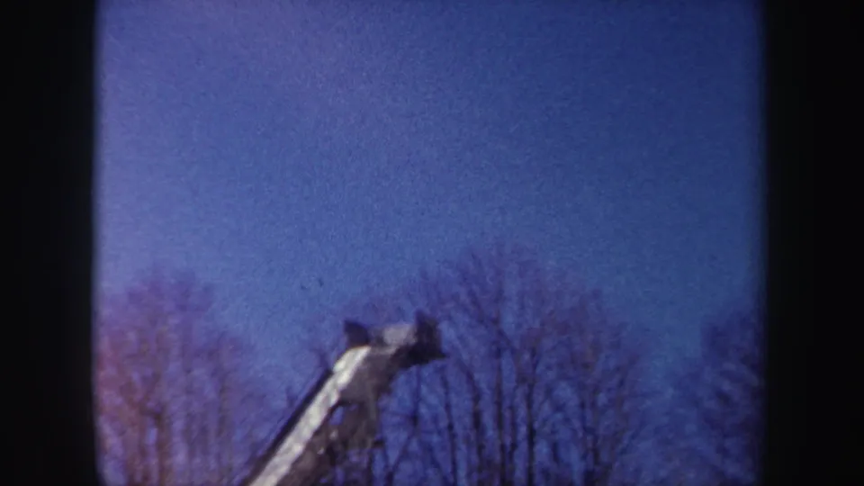 1962 New York 8mm frame showing the elevated structure's upper end over a line of bare winter trees.