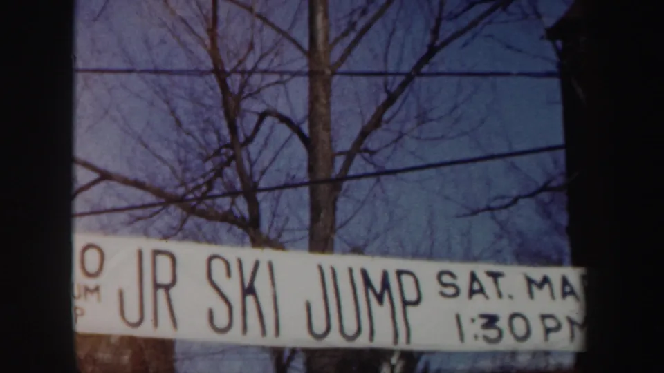 1962 New York 8mm frame focusing on the JR SKI JUMP banner with Saturday date and 1:30 PM time against winter trees.