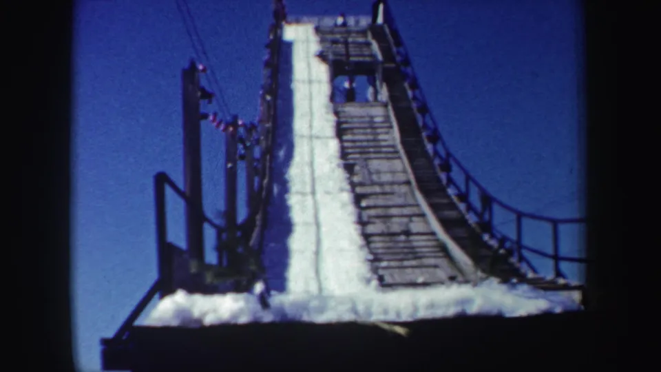 Closer 1962 New York 8mm view of the ski jump ramp surface, wooden decking, side railings, and snow piled along the run.