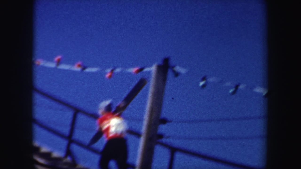 Person in a red and white top climbs a stairway while carrying skis under a blue sky.