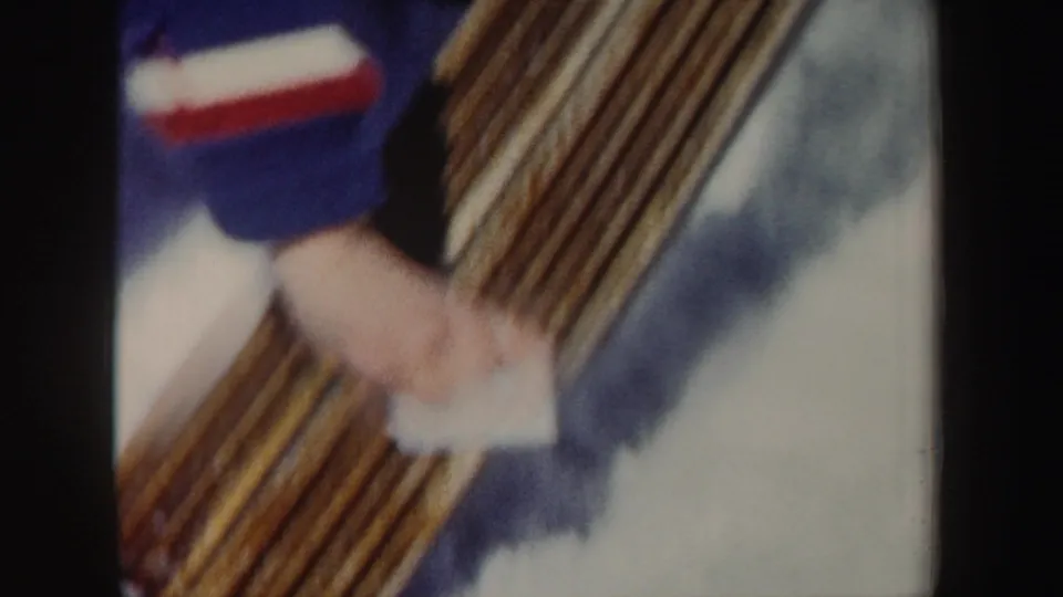 Soft, motion-blurred 1962 New York 8mm close-up of a skier working near a row of wooden skis on snow.