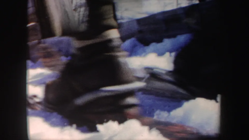 Soft 8mm frame showing a close, blurred view of a skier's lower legs or boots over snow in the New York winter sports clip.