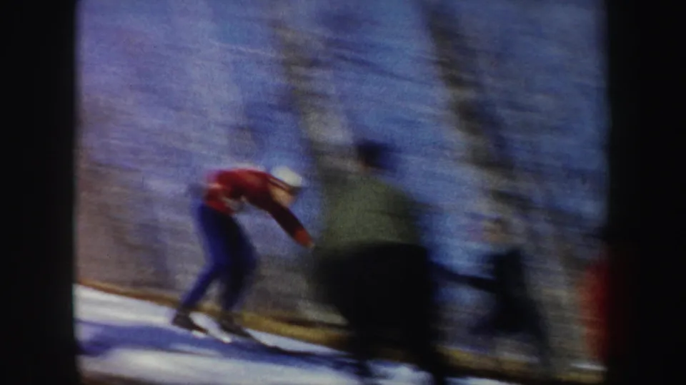 A skier passes through the frame on a snowy slope in the New York winter footage, with motion blur and bare trees behind.