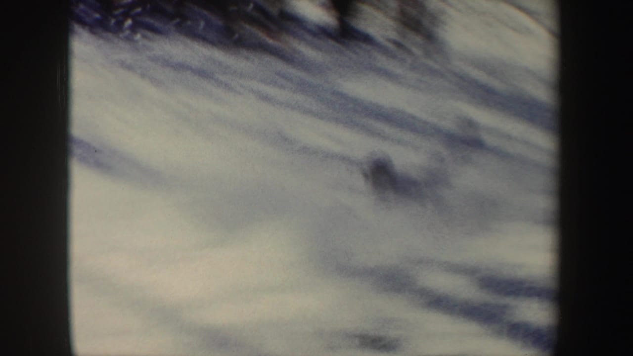 Blurred snowy slope seen through dark vertical film edges.