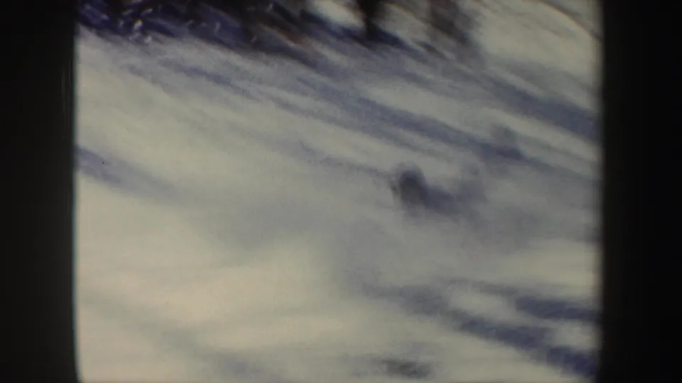 Soft 8mm view of a snowy New York ski slope in 1962, with dark frame edges and indistinct movement on the snow.