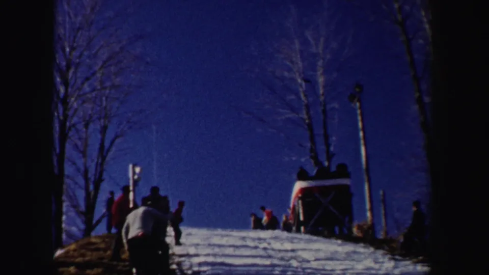 A 1962 New York ski slope scene shows bare trees, people on the snow, and a small slope-side structure under a deep blue sky.