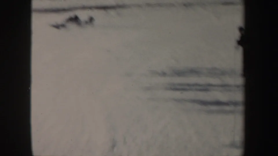 Soft 1962 New York 8mm frame of a snowy slope with a blurred figure low on the snow near the top of frame.
