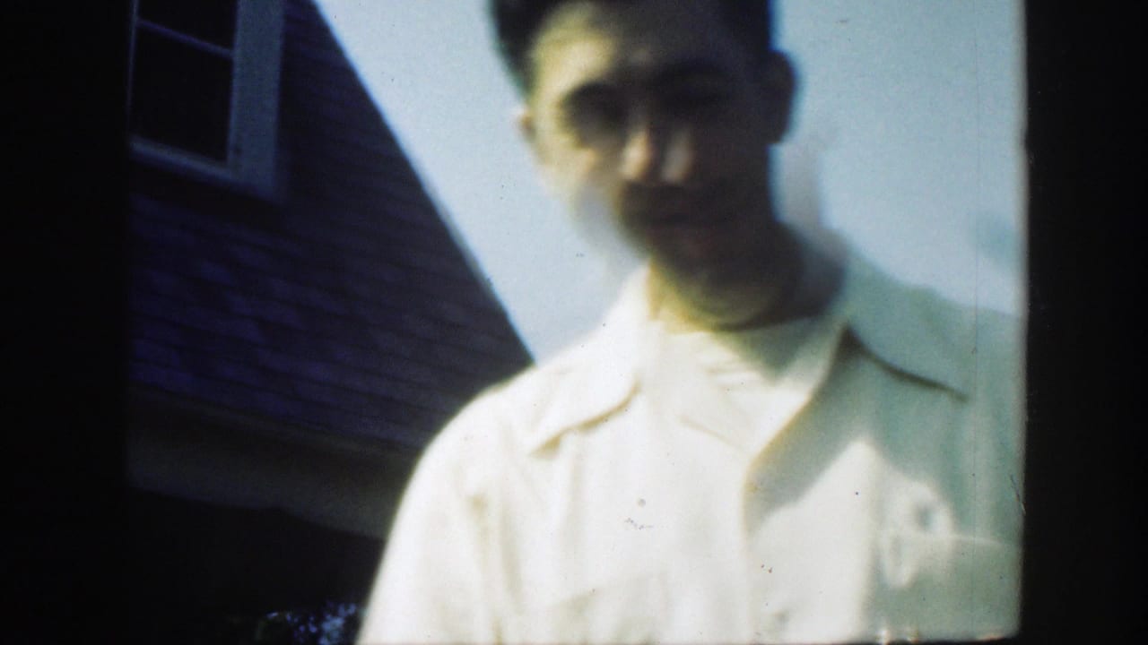 A man in a light short-sleeved shirt stands in soft focus outdoors in the 1949 Massachusetts home-movie scene.