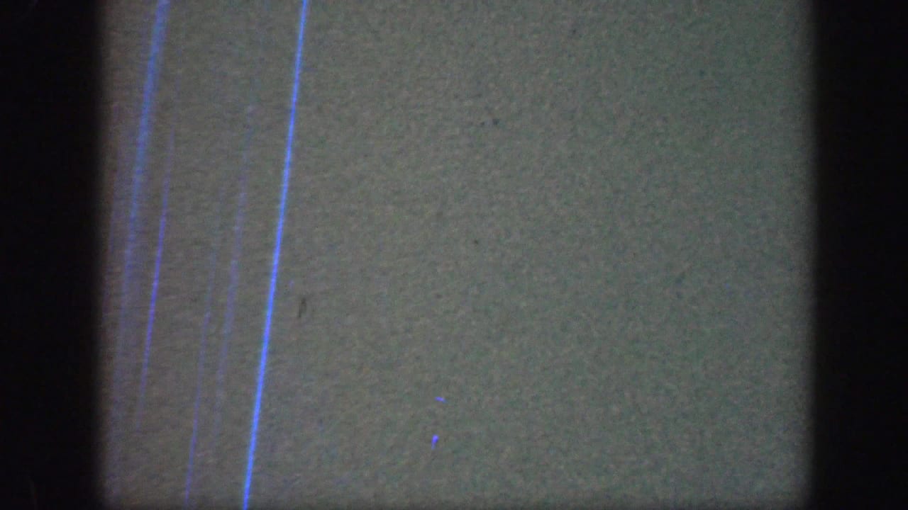 The final frame is largely obscured, showing film texture, dark borders, and blue vertical marks rather than a clear subject.