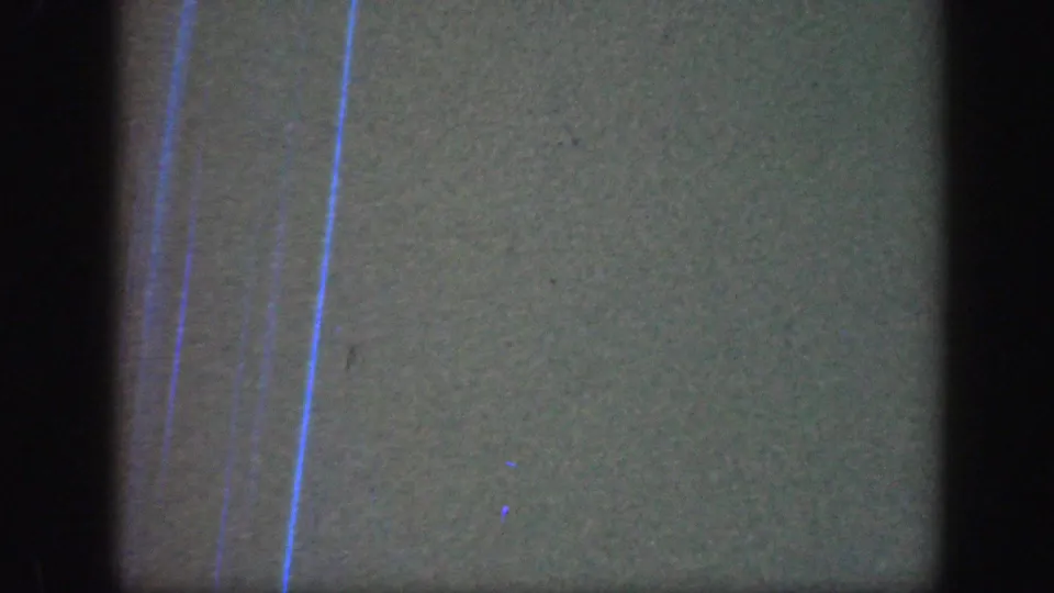 The final frame is largely obscured, showing film texture, dark borders, and blue vertical marks rather than a clear subject.
