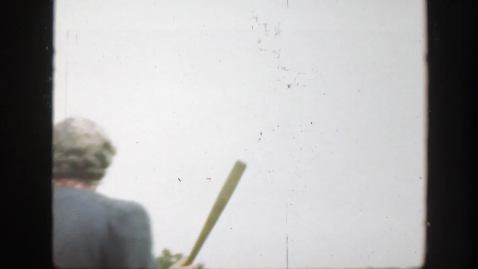 The woman turns away while holding a wooden baseball bat, with trees low in the frame and bright sky behind her.