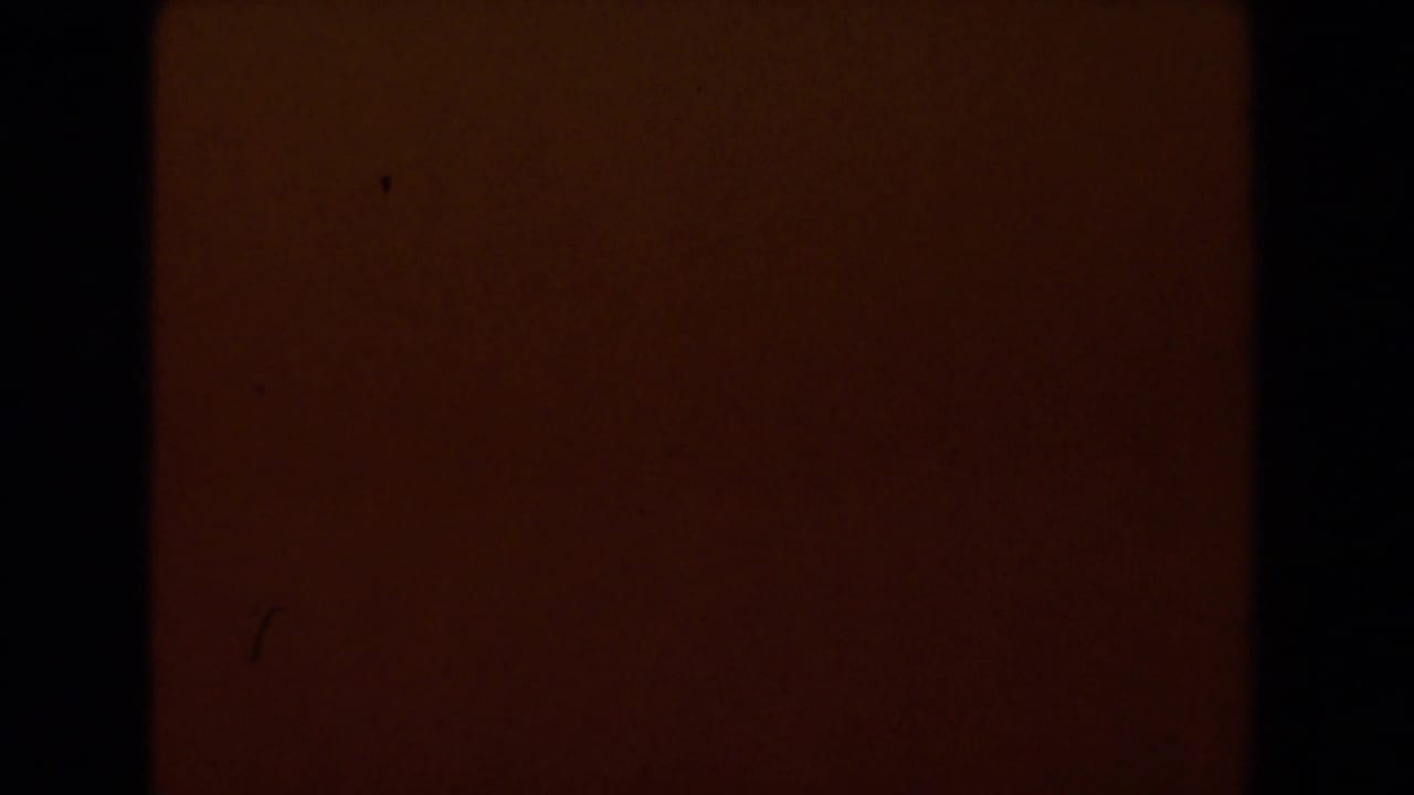 Dark red-orange field with black frame edge and visible film grain.