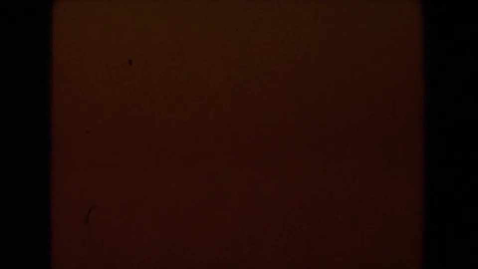 1962 Glendale 8mm frame showing a dark red-orange exposure field with black border, grain, and faint marks.