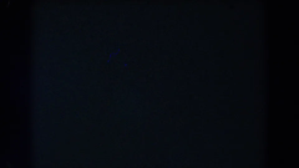 Dark blue-green abstract 8mm frame with a central black vertical band, grain, and low exposure.